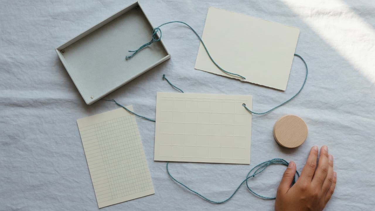 Blank workflow cards, an inbox tray and a ledger grid connected by teal cord to a human approval token