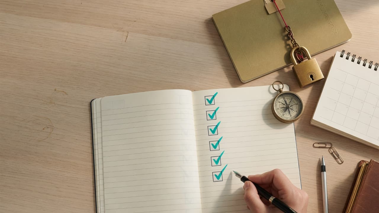An open checklist notebook on a warm desk with teal ticks, a folder, padlock, calendar and compass